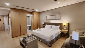 A modern hotel room with a large bed, a wardrobe, a bedside table, and a chair. - Signature Apartment at 188 Suites (Kuala Lumpur)