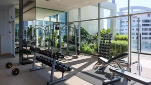 A modern gym with various exercise equipment, large windows, and a view of greenery and buildings. - Signature Apartment at 188 Suites (Kuala Lumpur)