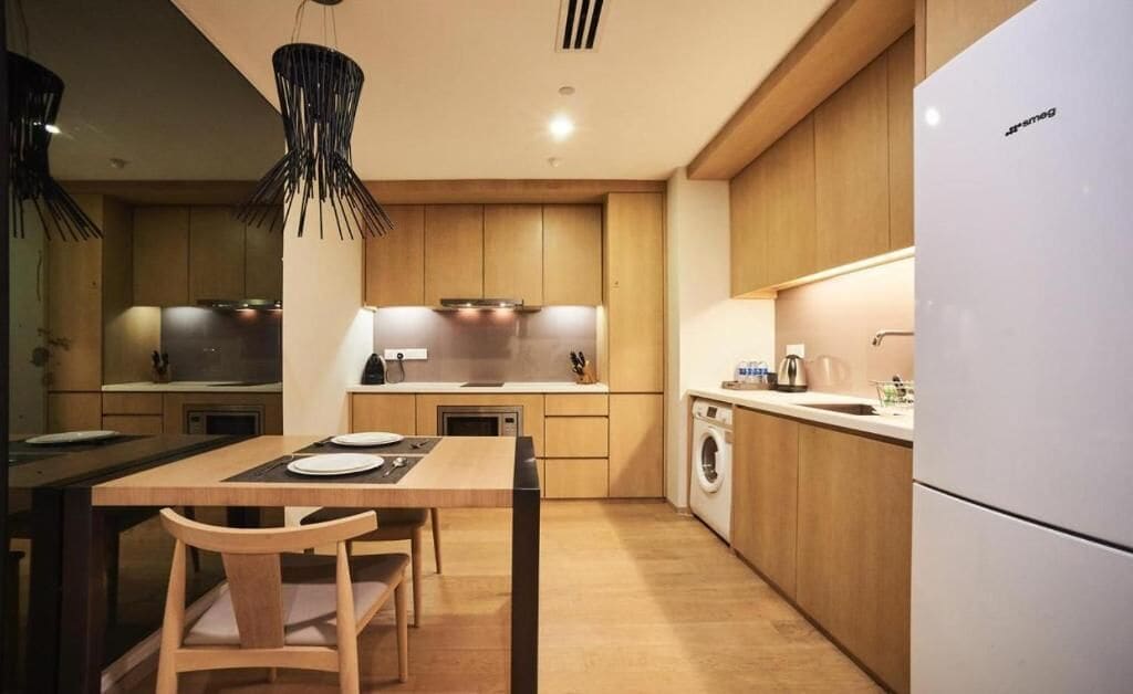 A modern kitchen with wooden cabinets, a built-in oven, a sink, and a dishwasher.