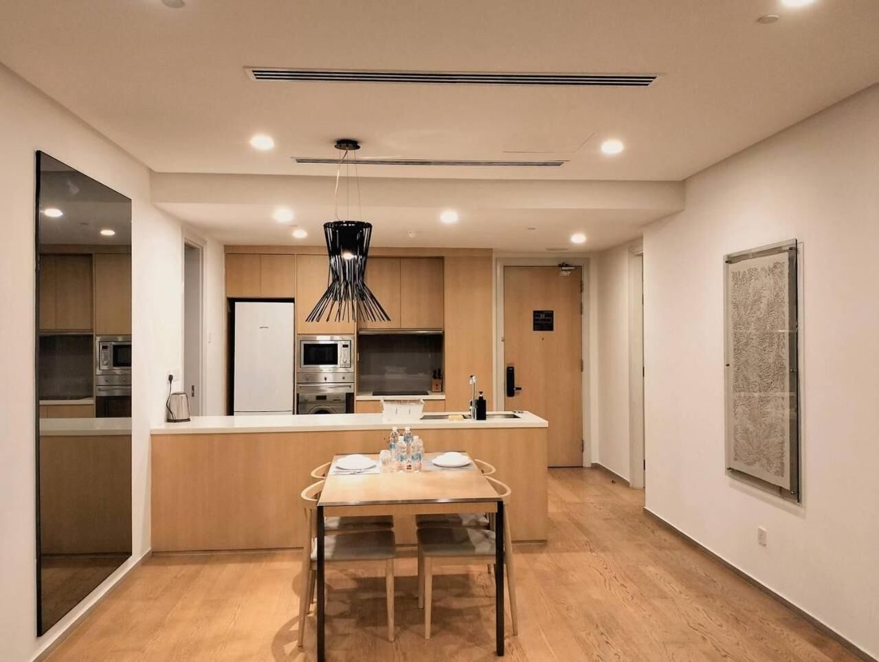 A modern kitchen with wooden cabinets, a central island, and a hanging light fixture.