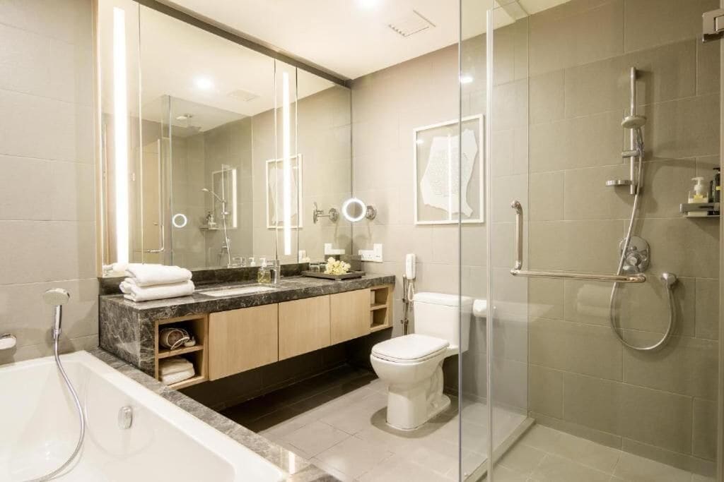 A modern bathroom with a glass shower enclosure, a bathtub, a toilet, and a vanity with a mirror.