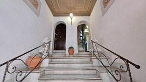 Eine Marmortreppe mit aufwendigen Metallgeländern, die zu einer dunklen Holztür führt.