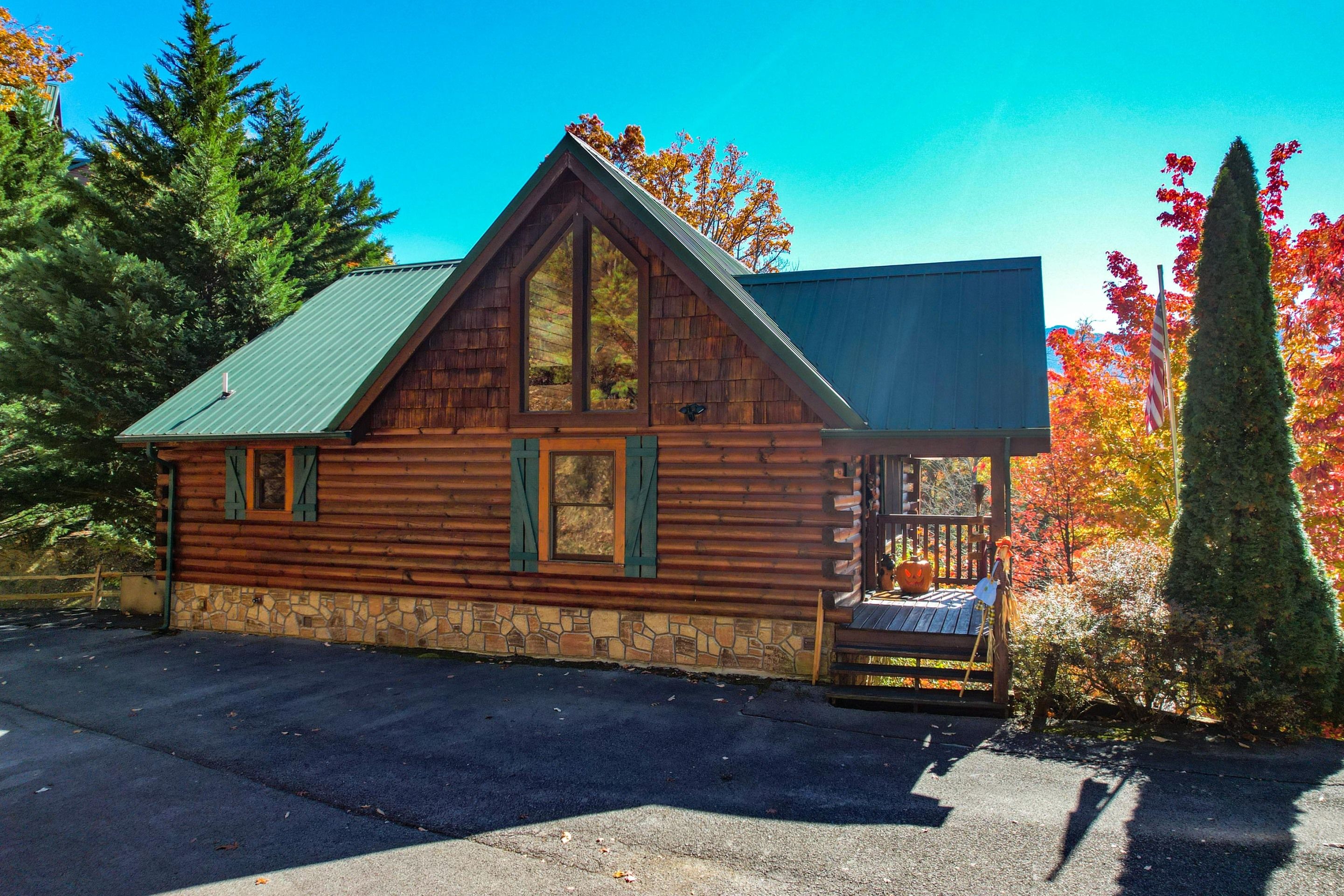 Une cabane en rondins, avec des fondations en pierre, un toit à forte pente et une véranda dotée d’une balustrade.