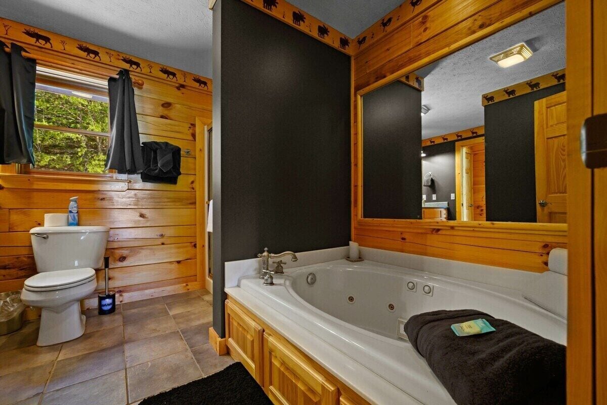 A bathroom with a wooden interior, a white bathtub, and a toilet.