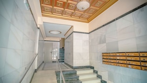 Un pasillo con suelo de mármol, una escalera y un techo con paneles decorativos.
