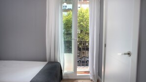 Un dormitorio con una cama, una ventana y una puerta que da a un balcón.