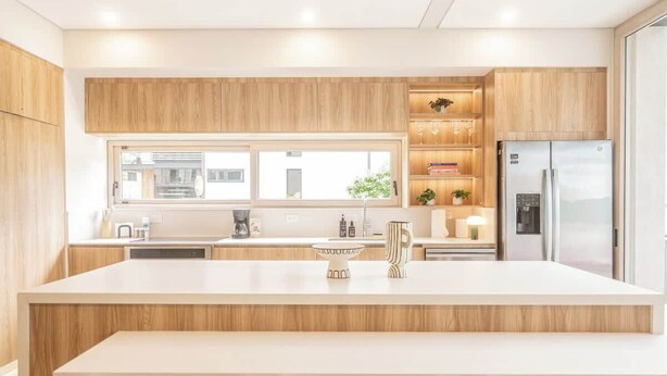 Une cuisine moderne avec des meubles en bois, un îlot central et un réfrigérateur encastré.