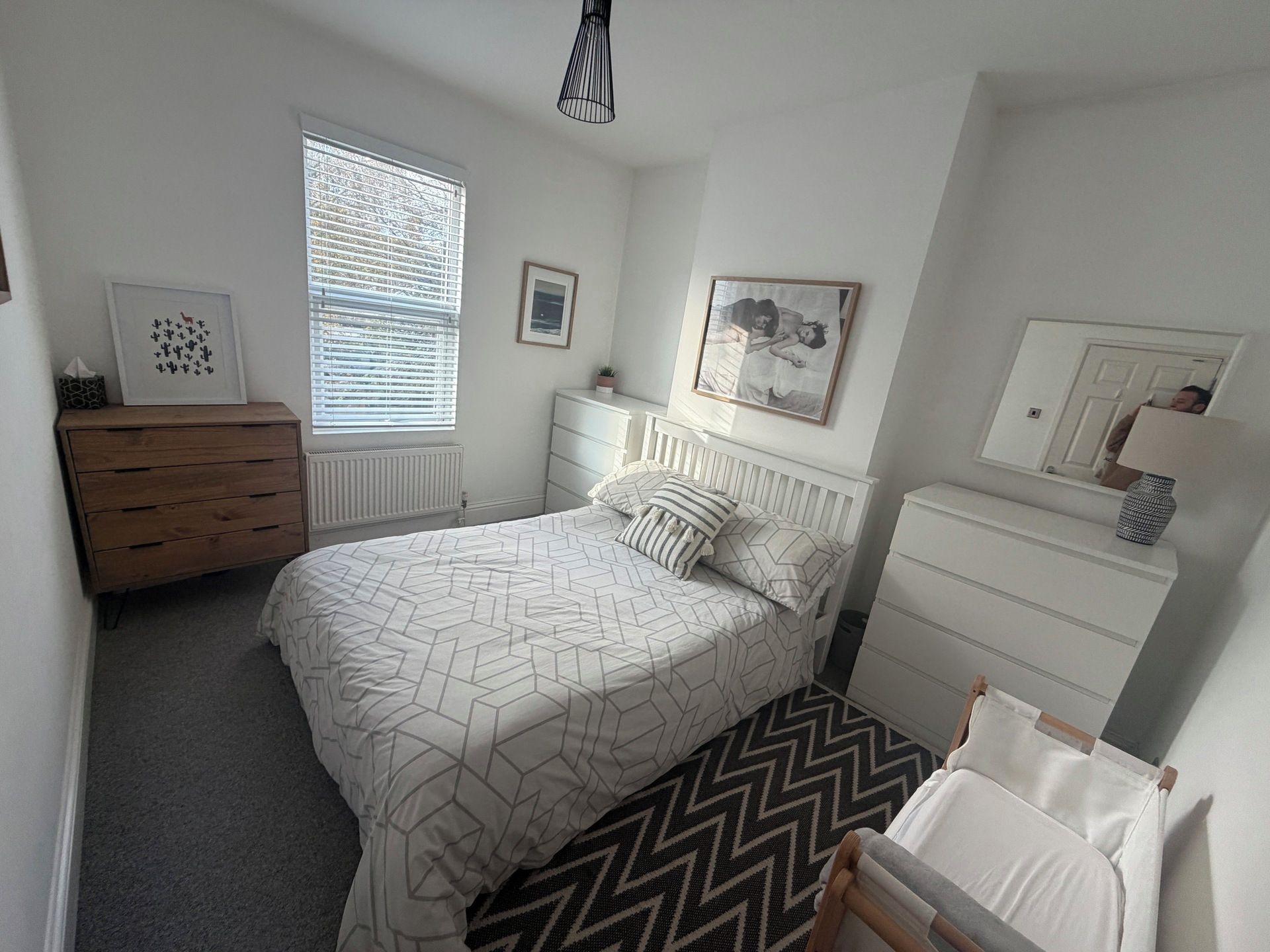 Een slaapkamer met een bed, een kaptafel, een nachtkastje en een spiegel.