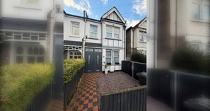 A residential street with houses, a gated entrance, and a checkered pathway. - Cozy and Convenient Raynes Park maisonette (Greater London)
