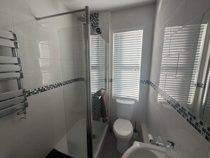 A bathroom with a glass-enclosed shower, a toilet, and a sink. - Cozy and Convenient Raynes Park maisonette (Greater London)