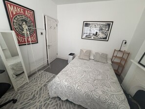 A bedroom with a bed, a wardrobe, a radiator, a framed picture on the wall, and a poster on the wall. - Cozy and Convenient Raynes Park maisonette (Greater London)