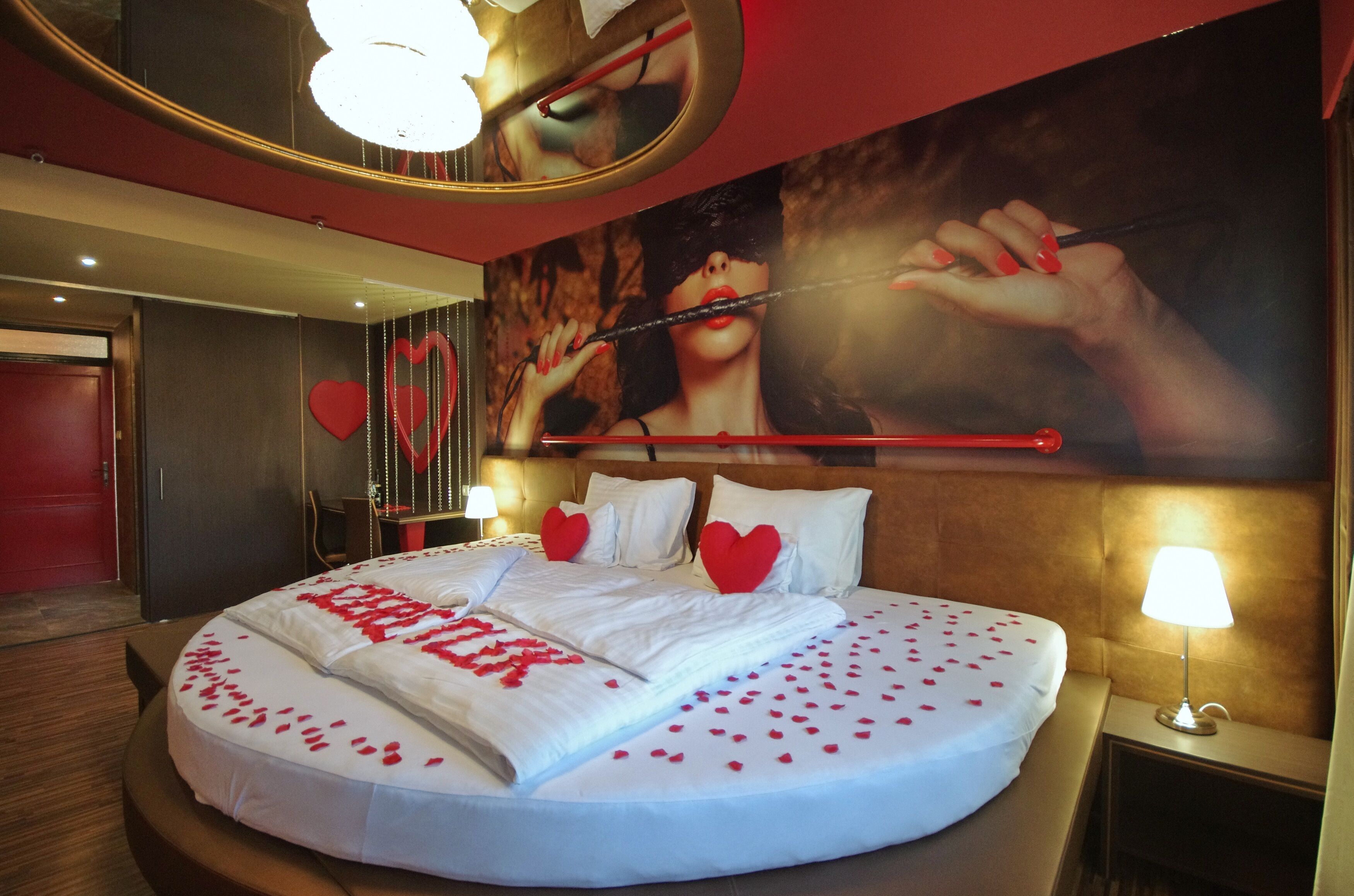 Habitació d'hotel amb un llit gran, almoinades amb forma de cor i una paret amb un cartell gran.