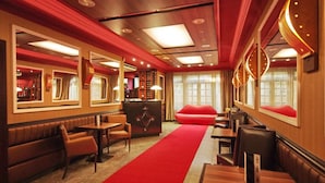 A restaurant with a red carpet, wooden walls, and leather seating.