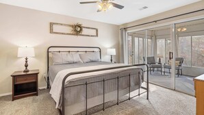 A bedroom with a bed, nightstands, a ceiling fan, and a sliding glass door leading to a balcony. - Premiere Pointe with Golf Discounts (Branson)