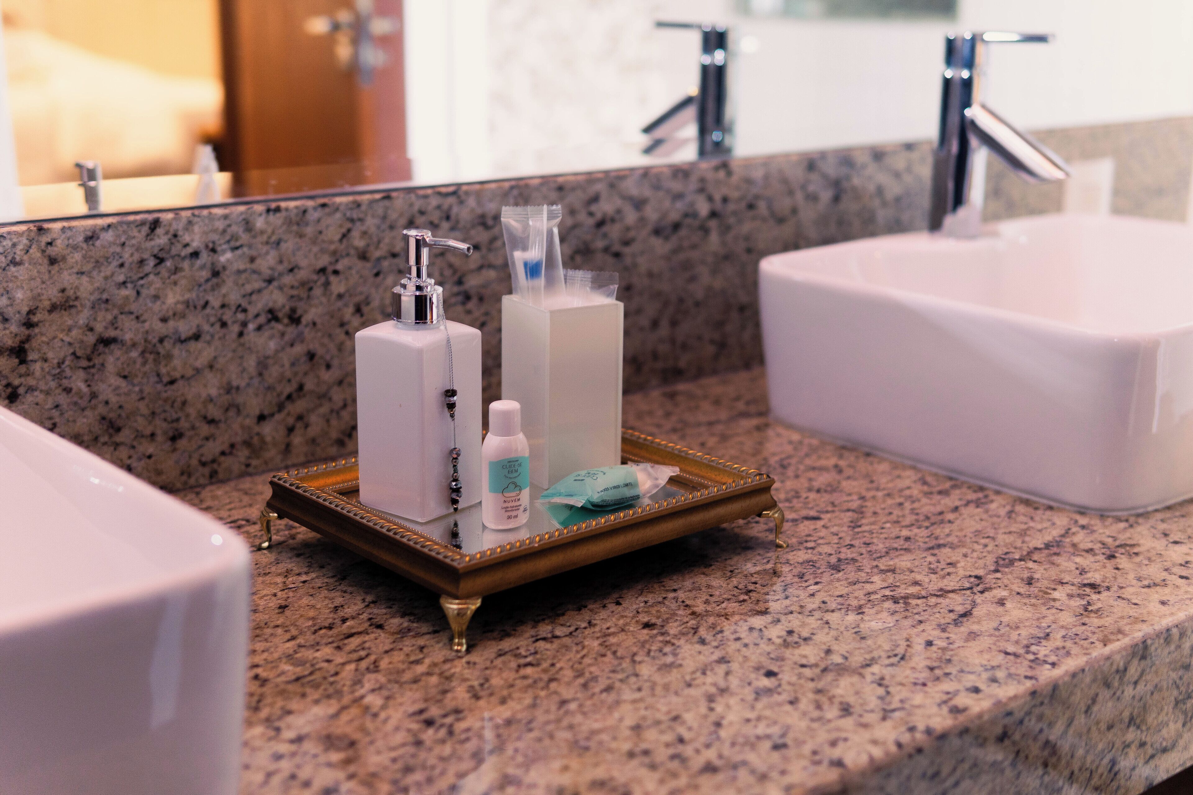 Un baño con encimera de granito, un lavamanos blanco y un espejo.