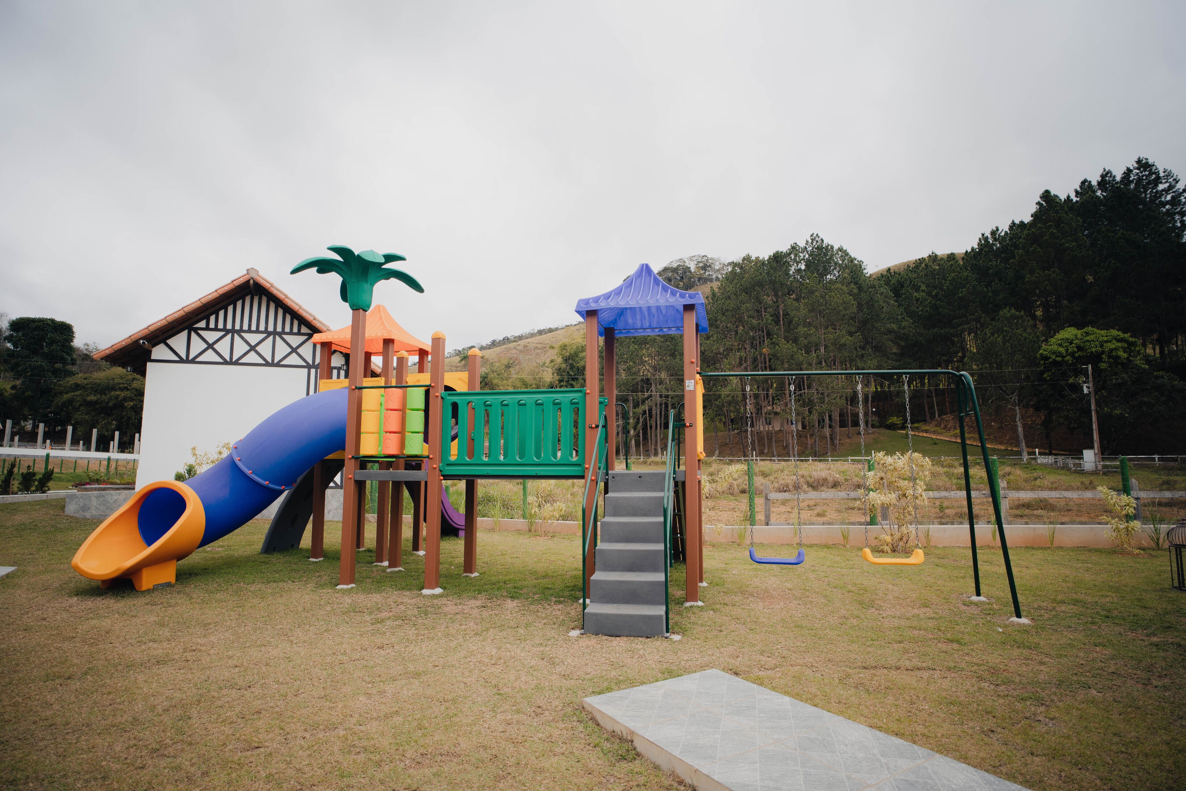 Un parque infantil con tobogán, estructuras de escalada y columpios.