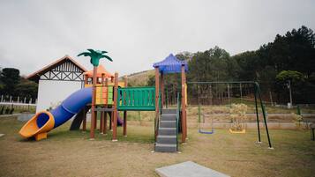 Un parque infantil con tobogán, estructuras de escalada y columpios.