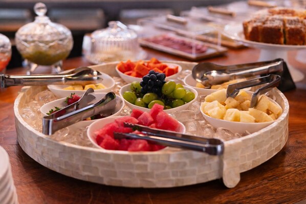 A buffet with various fruits and desserts on a round table with ice.