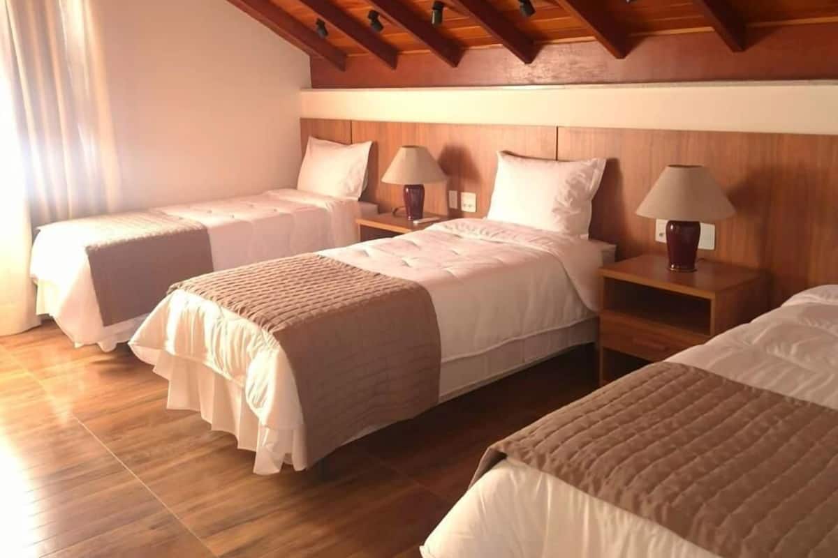 Ein Zimmer mit zwei Betten, Holzboden und einer schrägen Decke mit freiliegenden Balken.
