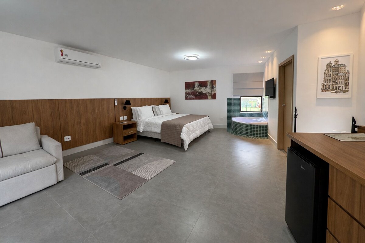 Une chambre d’hôtel moderne équipée d’un lit, d’un canapé, d’un petit bureau et d’une salle de bain avec baignoire.