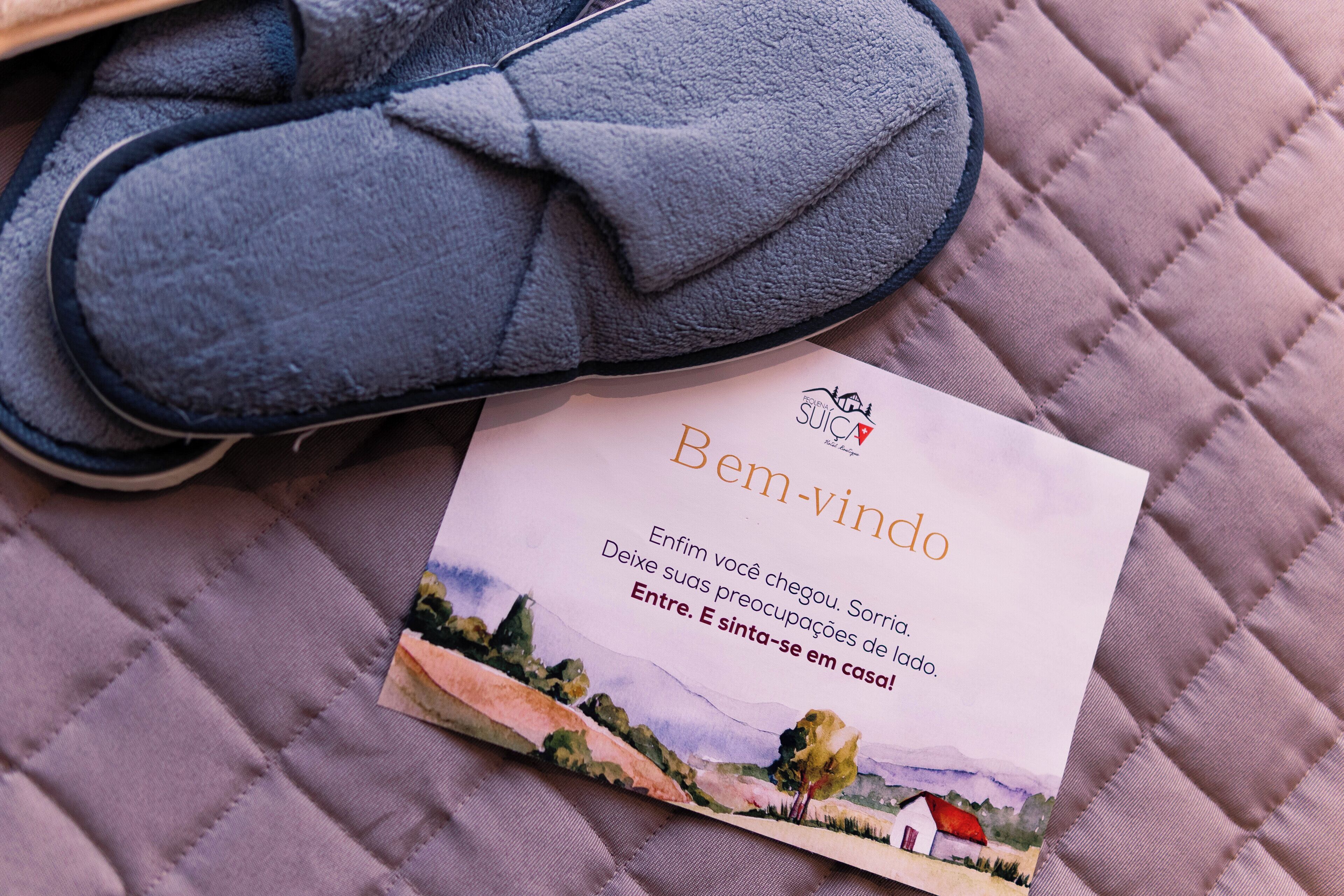 A pair of blue slippers and a welcome card with a landscape illustration.