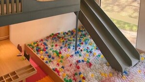 A children's play area with a ball pit, a slide, and a window with a view of the outdoors. - Pequena Suíça Hotel Boutique (Chacara)