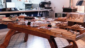 A buffet table with various food items and a coffee machine in the background. - Pequena Suíça Hotel Boutique (Chacara)