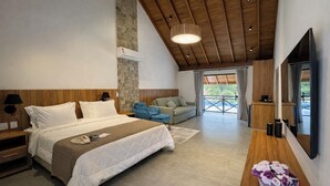 A modern bedroom with a large bed, a wooden ceiling, a stone wall, a sofa, and a TV. - Pequena Suíça Hotel Boutique (Chacara)