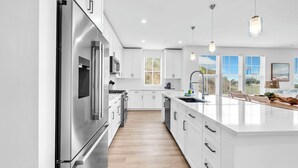 A modern kitchen with white cabinetry, stainless steel appliances, and a large island with a sink. - The Grove Dogwood 321 - 4 Bedrooms - Lazy River - Seascape Resort (Miramar Beach)