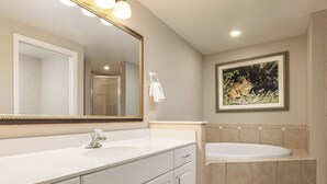 Ein Badezimmer mit einem weißen Waschtisch, einem großen Spiegel, einer Badewanne und einem gerahmten Bild an der Wand.