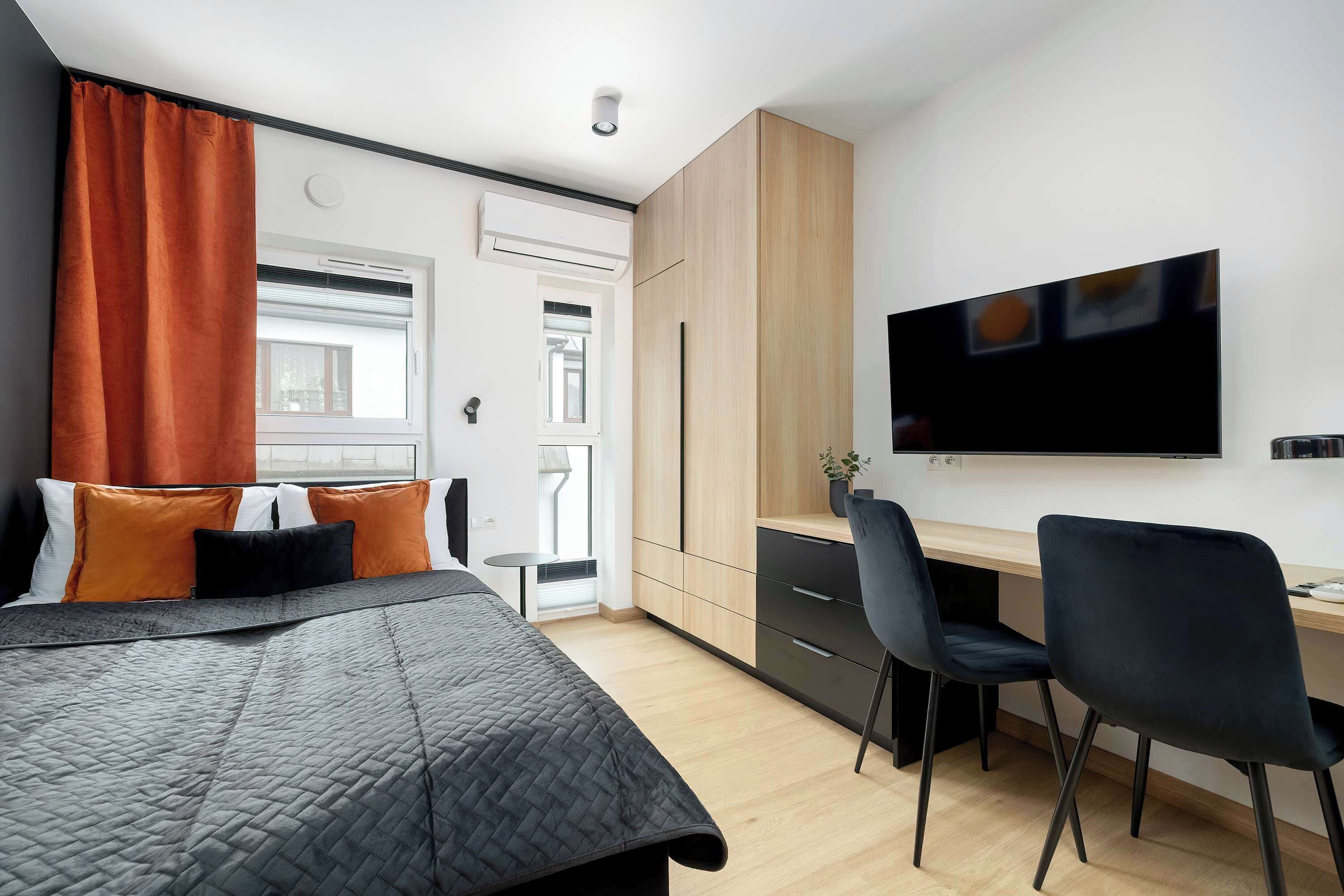 A modern bedroom with a bed, a desk, and a TV.