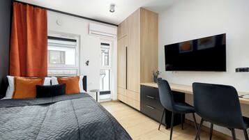 A modern bedroom with a bed, a desk, and a TV.