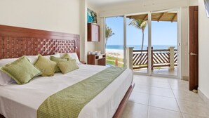 A hotel room with a bed, a view of the beach, and a sliding glass door to the outside. - Four bedroom, ocean front, Vivo Resorts, Palmarito (Bajos de Chila)