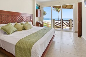 A hotel room with a bed, a view of the beach, and a sliding glass door to the outside.