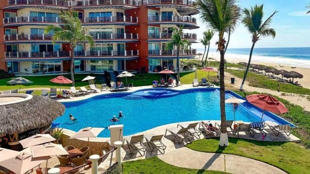 A hotel with a large pool, multiple balconies, and a beach view. - Four bedroom, ocean front, Vivo Resorts, Palmarito (Bajos de Chila)