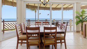 A dining area with a view of the ocean, wooden chairs, a table, and a potted plant. - Four bedroom, ocean front, Vivo Resorts, Palmarito (Bajos de Chila)