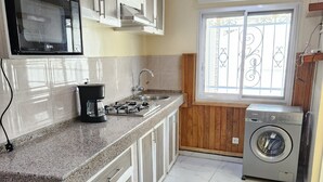 A kitchen with a microwave, coffee maker, sink, and washing machine. - Luxury villa (Douala)