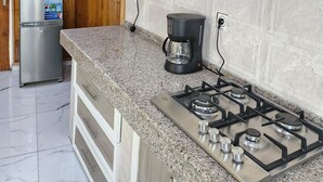 A kitchen with a gas stove, a coffee maker, a microwave, and a refrigerator. - Luxury villa (Douala)