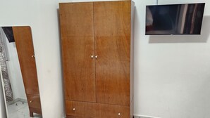 A room with a wooden wardrobe, a flat-screen TV mounted on the wall, and a tiled floor. - Luxury villa (Douala)