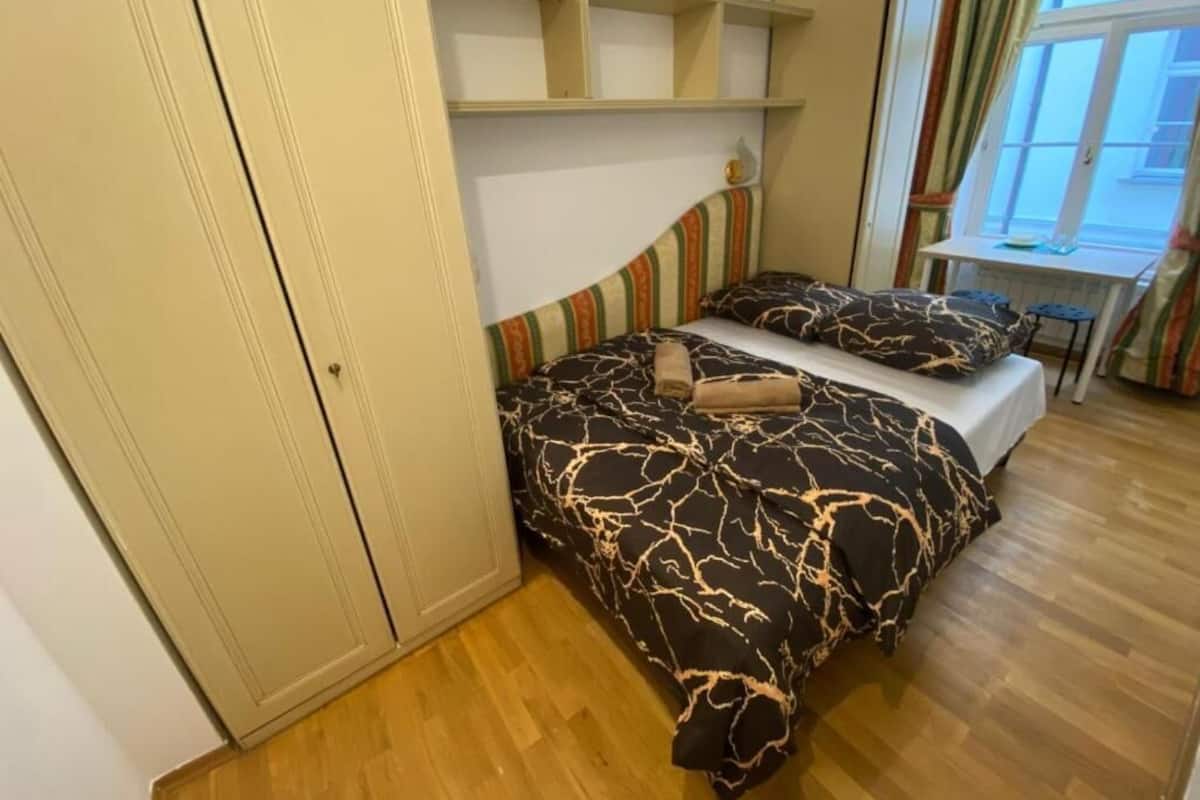 A bedroom with a bed, a wardrobe, and a window.