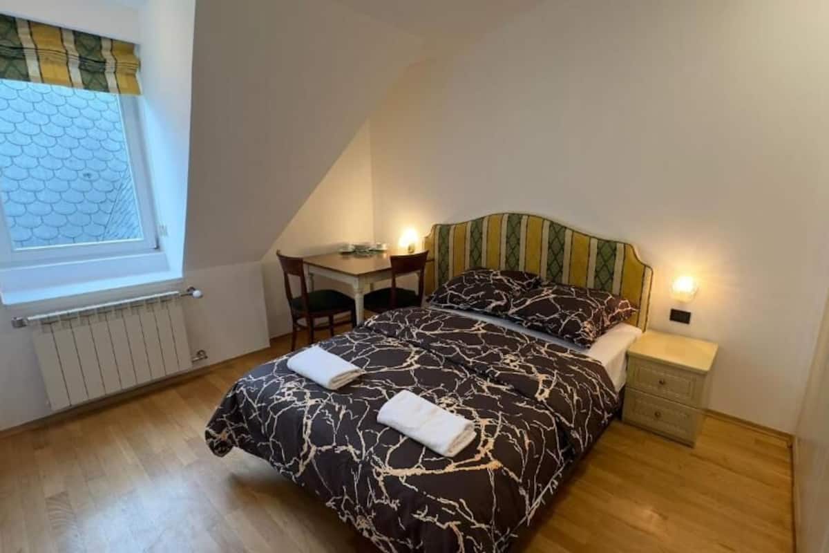 A bedroom with a bed, bedside tables, a desk, and a chair.