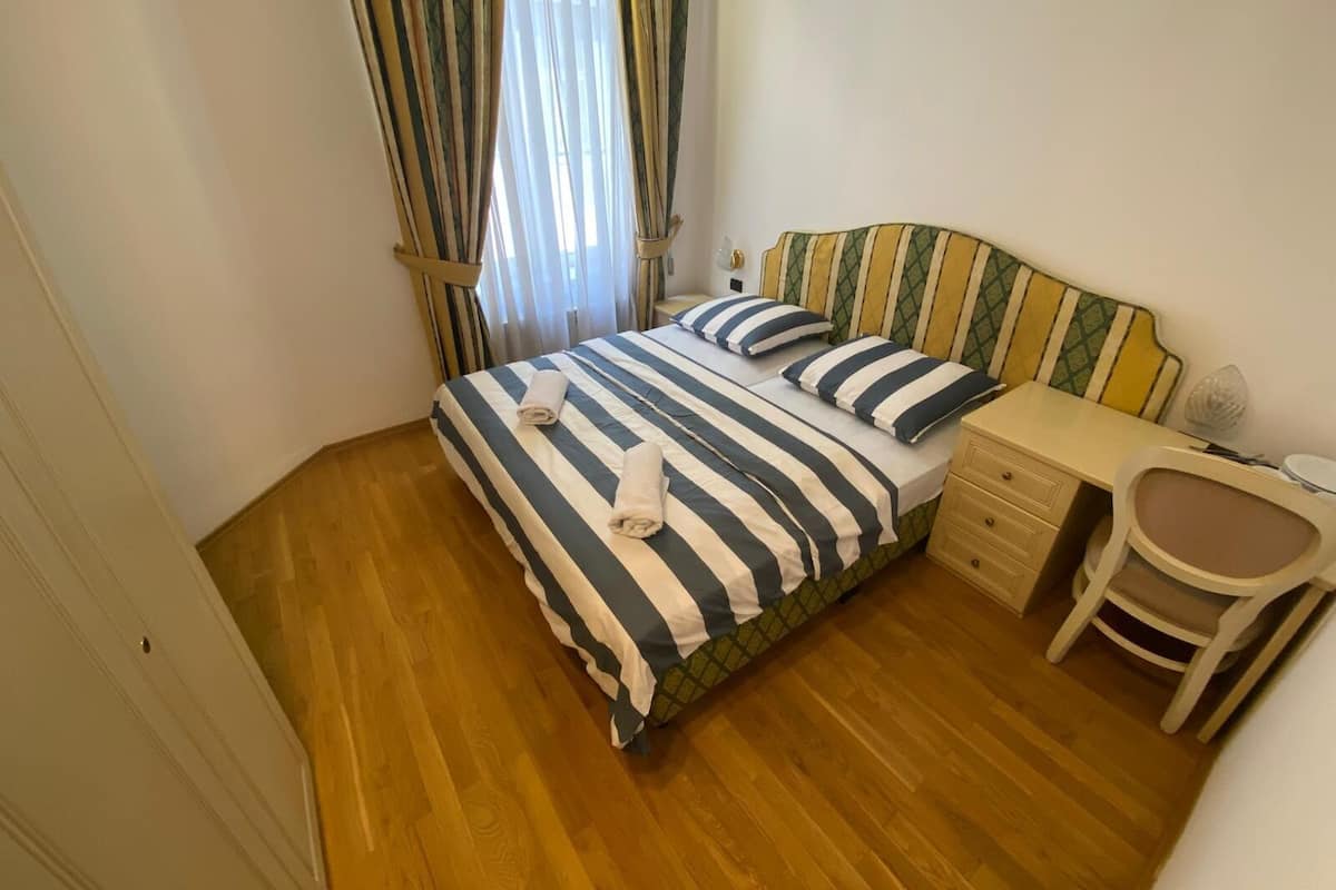 A bedroom with a bed, a nightstand, a chair, and a desk.