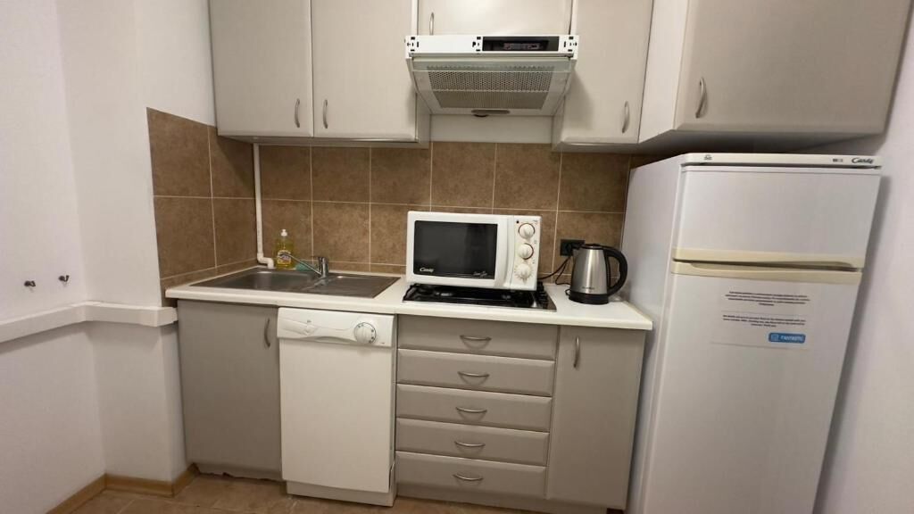 Eine kleine Küche mit Mikrowelle, Wasserkocher und Kühlschrank.
