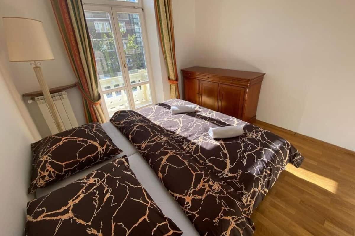 A bedroom with a bed, a wooden cabinet, and a window with curtains.