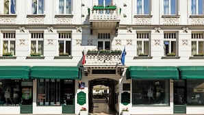 Un edificio grande y histórico con varios balcones, una entrada central y banderas.