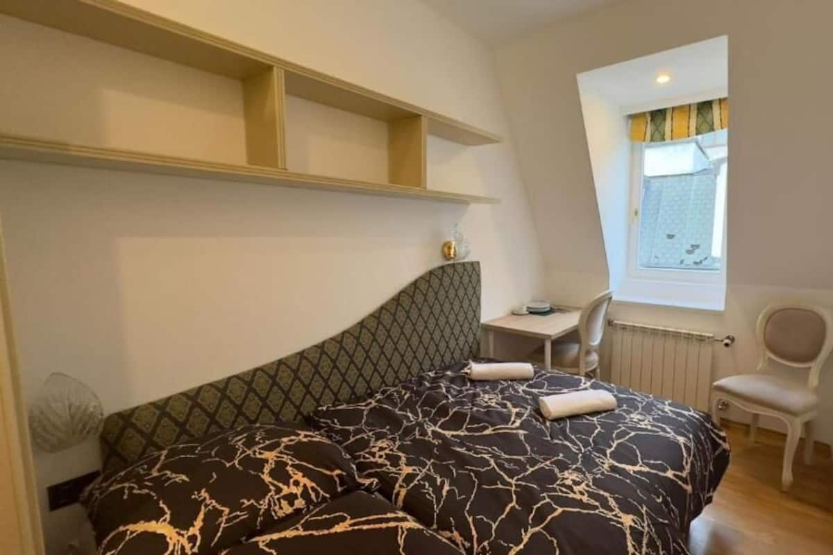 A bedroom with a bed, a desk, and a chair.