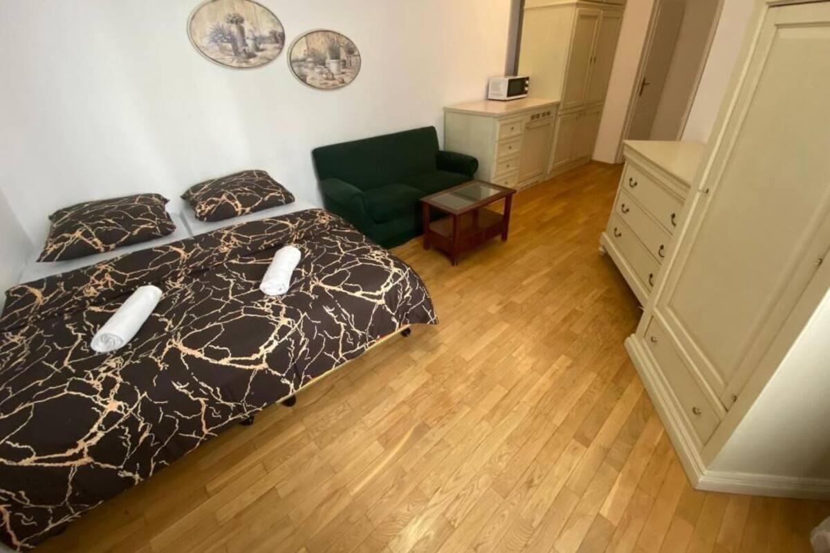 A bedroom with two beds, a green sofa, a small table, and a wardrobe.