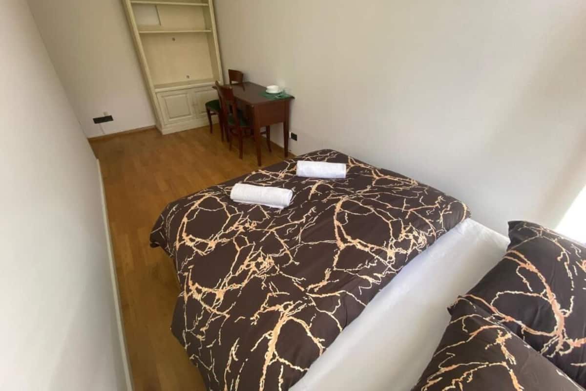 A bedroom with a bed, two pillows, a desk, and a chair.