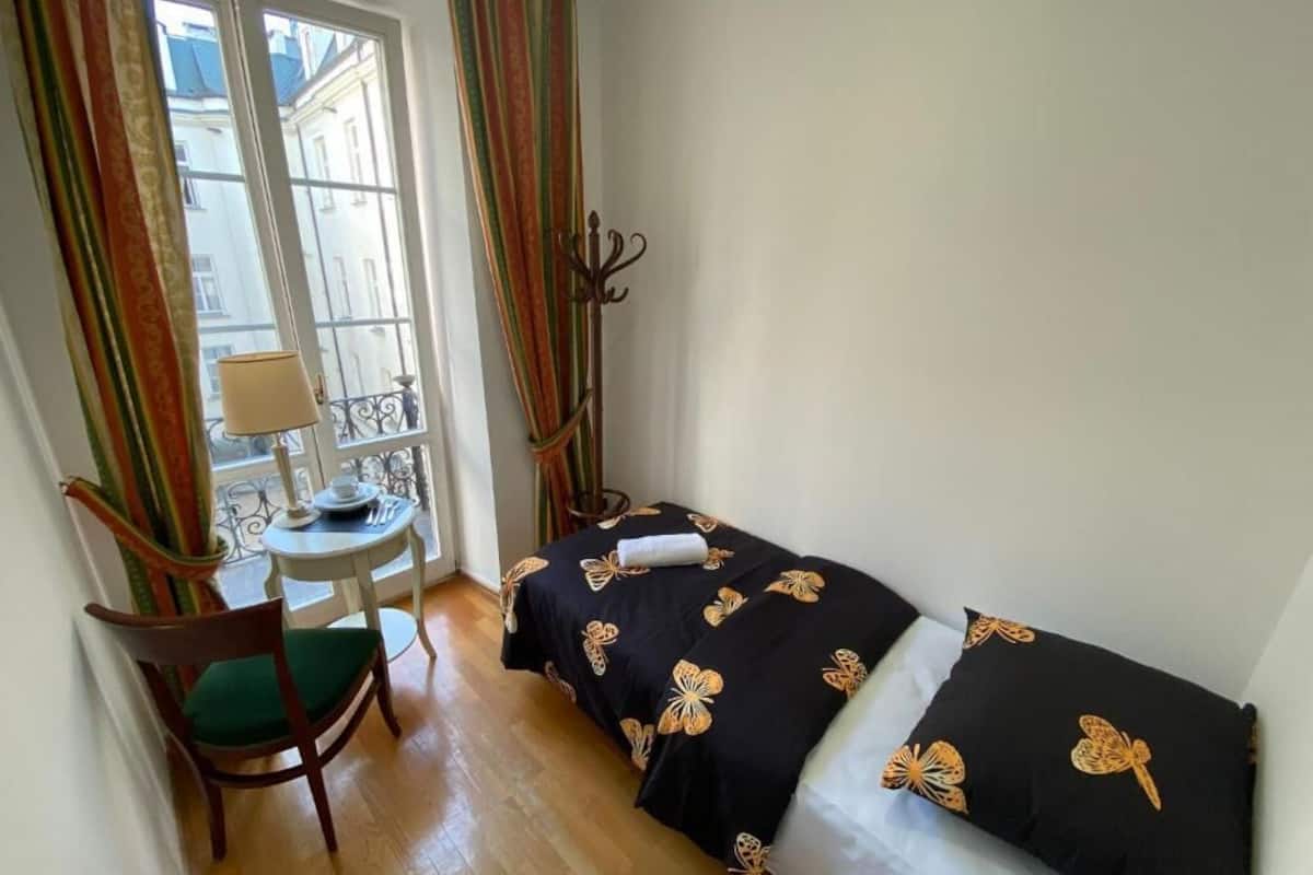 A small room with a bed, a chair, a table, and a window with curtains.