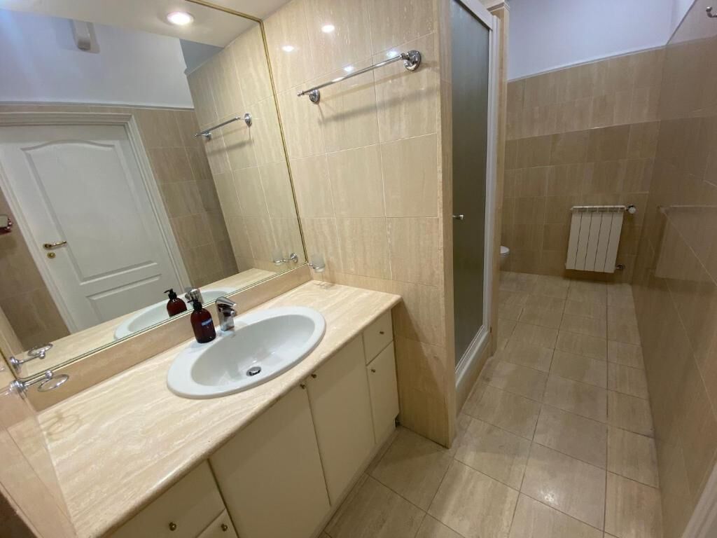 A bathroom with a sink, mirror, and shower.